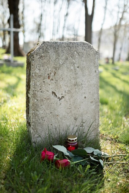 Blick auf den Grabstein mit Blumen und Kerzen