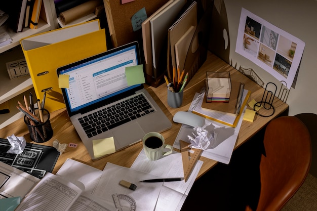 Blick auf den Schreibtisch mit unordentlichem Arbeitsplatz und Laptop