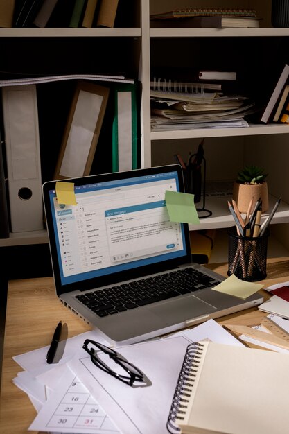 Blick auf den Schreibtisch mit unordentlichem Arbeitsplatz und Laptop