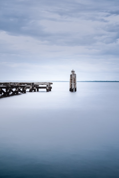 Blick auf ein ruhiges Meer in der Nähe eines Holzdocks an einem düsteren Tag