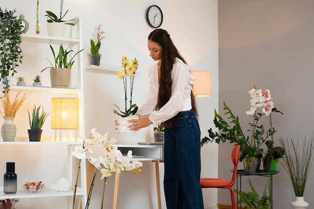 Kostenloses Foto blick auf eine frau, die ihr zuhause mit orchideeblumen schmückt