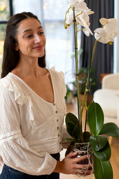 Kostenloses Foto blick auf eine frau, die ihr zuhause mit orchideeblumen schmückt