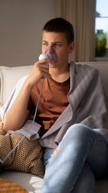 Blick auf einen Teenager, der zu Hause einen Vernebler wegen Atemwegsproblemen verwendet