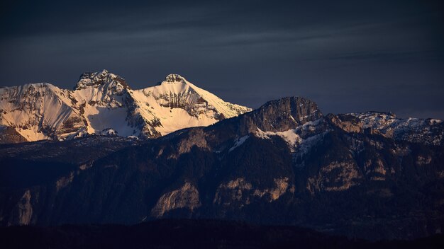 Blick auf felsige Berge, die während des Sonnenuntergangs mit Schnee bedeckt werden