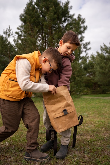 Kostenloses Foto blick auf kleine jungen mit rucksäcken, die draußen zeit in der natur verbringen