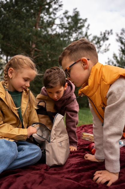 Kostenloses Foto blick auf kleine kinder mit rucksäcken, die draußen zeit in der natur verbringen