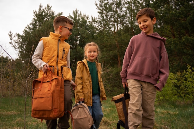 Kostenloses Foto blick auf kleine kinder mit rucksäcken, die draußen zeit in der natur verbringen