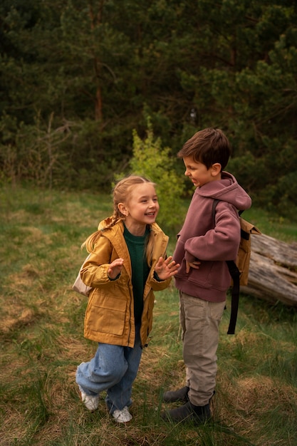 Blick auf kleine Kinder mit Rucksäcken, die draußen Zeit in der Natur verbringen