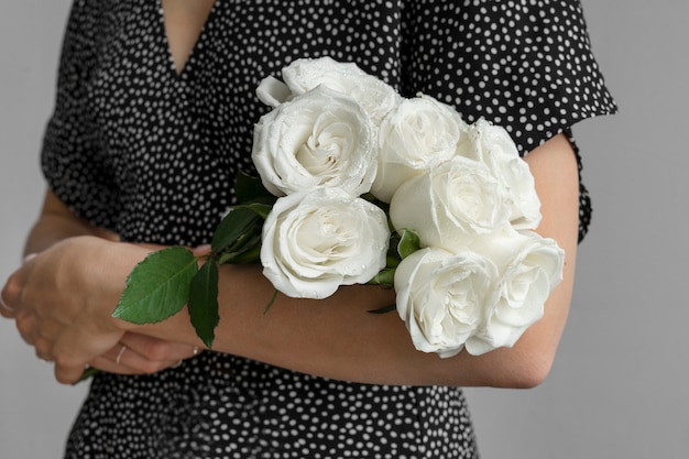 Blick auf zarte weiße Rosen, die von einer Person gehalten werden