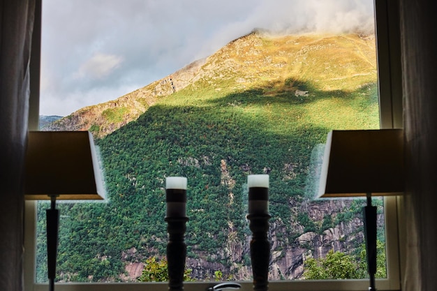 Kostenloses Foto blick aus dem fenster eines hauses auf einem wunderschönen berggipfel in norwegen bei sonnenuntergang.