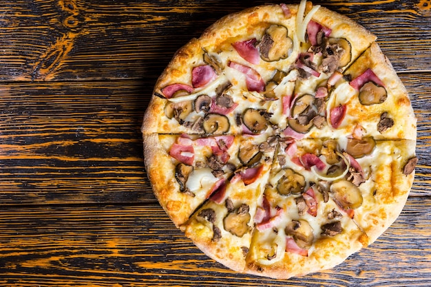 Blick aus der vogelperspektive auf leckere pizza mit schinken, pilzen, zwiebeln und gurken auf holztisch Premium Fotos