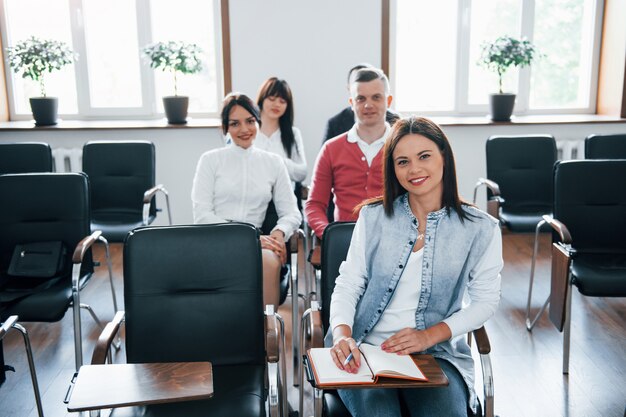 Blick in die Kamera. Gruppe von Personen an der Geschäftskonferenz im modernen Klassenzimmer tagsüber