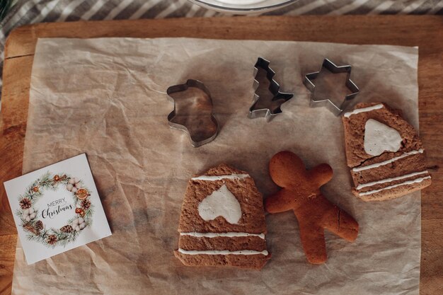 Blick über die moderne Küche mit weißen Schränken und braunem Tisch, dekoriert mit natürlichen grünen Tannenzweigen und Weihnachtskranz. Weihnachtsdekorationen.