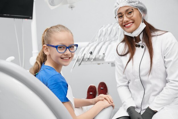 Blick von der Seite des glücklichen Mädchens, das in der Zahnarztpraxis sitzt