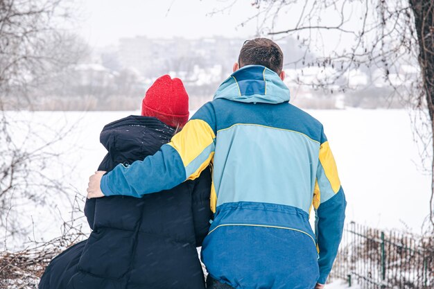 Blick von hinten eine junge Frau und ein Mann schauen auf den schneebedeckten See