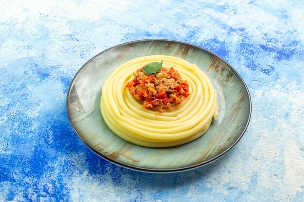 Blick von oben auf das Abendessen mit leckeren Spagetti auf einem grauen Teller auf blauem Hintergrund