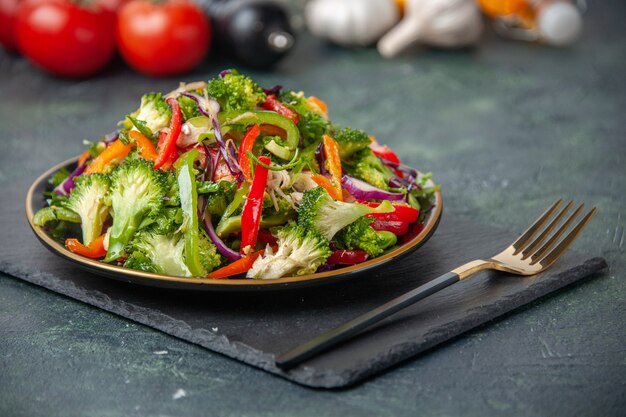 Blick von oben auf den Holzhammer der weißen Blume des frischen Gemüses und den köstlichen veganen Salat auf dunklem Farbhintergrund