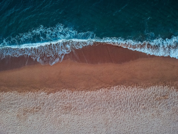 Blick von oben auf die Wellen am Sandstrand auf der Insel Kreta