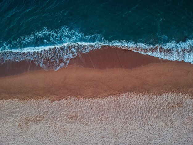 Blick von oben auf die Wellen am Sandstrand auf der Insel Kreta