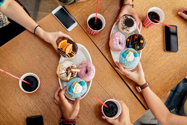Blick von oben auf Freunde, die glasierte Donuts essen, während sie sich in einem Café treffen