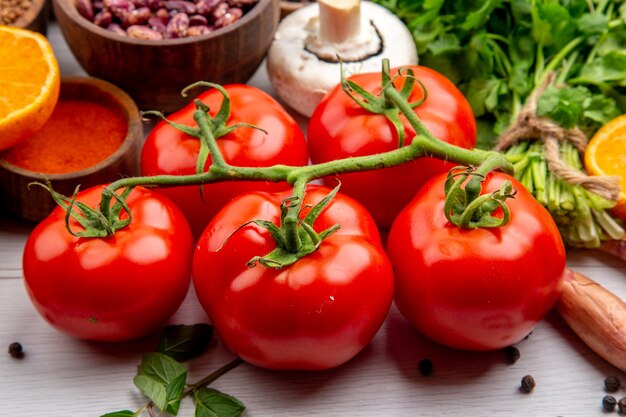 Blick von oben auf frische Tomaten mit Stiel braune Bohnenbündel aus grünen Pilzen auf weißem Hintergrund