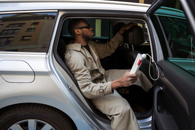 Blinder Mann der Seitenansicht, der aus dem Auto steigt