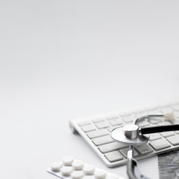Blisterpackung von Pillen und von Stethoskop mit drahtloser Tastatur auf weißem Hintergrund