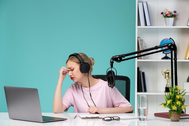 Blogger-Journalistin blondes süßes junges Mädchen, das Videos auf dem Computer im Büro aufnimmt, müde