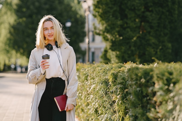 Blond geht in der Sommerstadt mit einer Tasse Kaffee spazieren