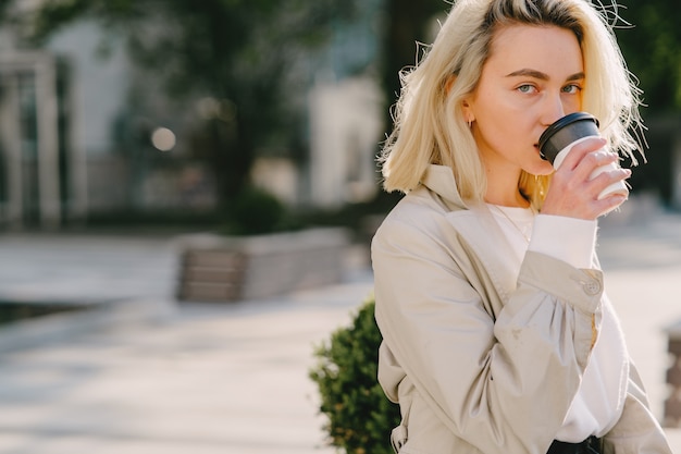 Kostenloses Foto blond in einer sommerstadt mit einer tasse kaffee