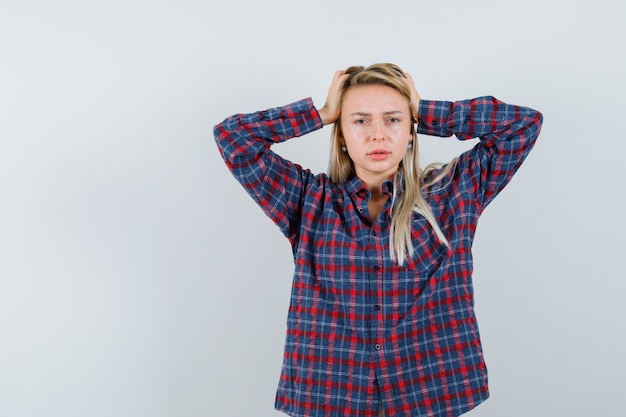 Kostenloses Foto blonde dame, die hände auf kopf im freizeithemd hält und wehmütig schaut. vorderansicht.