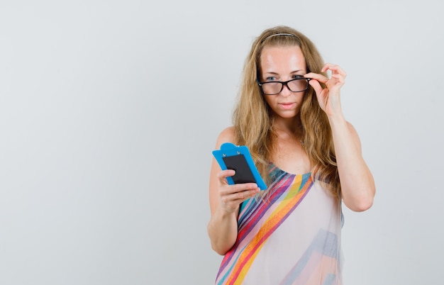 Blonde Dame, die über Notizen auf Zwischenablage im Sommerkleid schaut