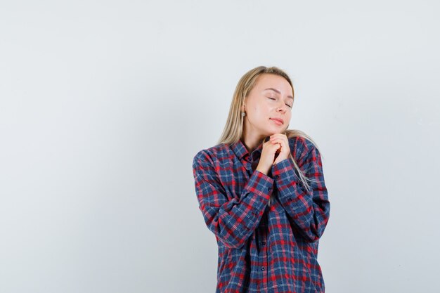 Blonde Dame im Freizeithemd hält Hände gefaltet und sieht friedlich aus, Vorderansicht.