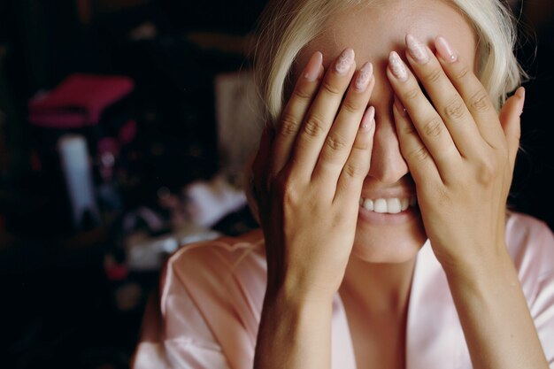 Blonde Dame lächelt, während sie ihr Gesicht hinter den Palmen verbirgt