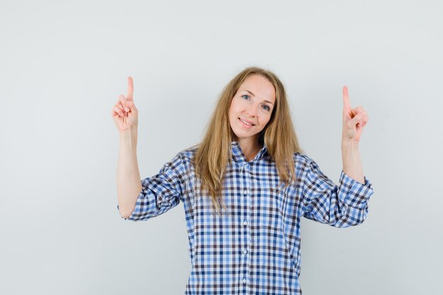 Blonde Dame zeigt im Hemd und sieht hoffnungsvoll aus.