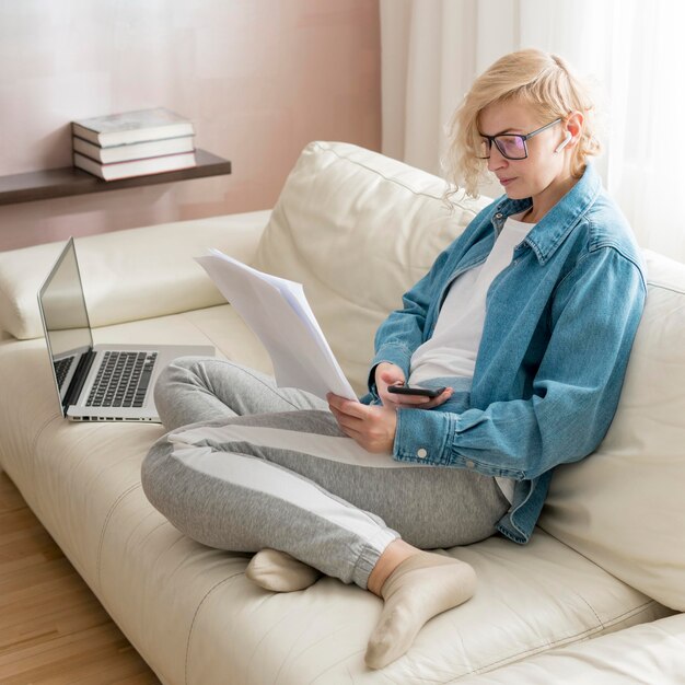 Blonde Frau, die auf Couch arbeitet