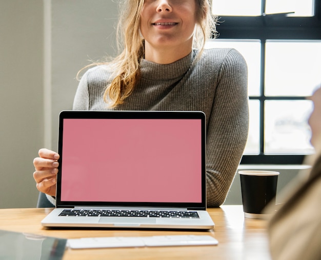 Blonde Frau, die auf einen Laptopbildschirm zeigt