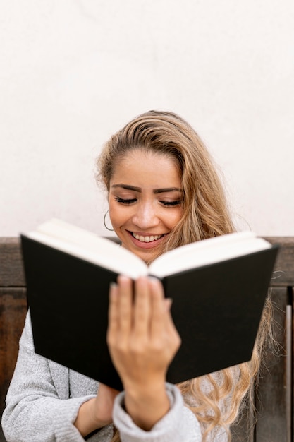 Blonde Frau, die draußen liest