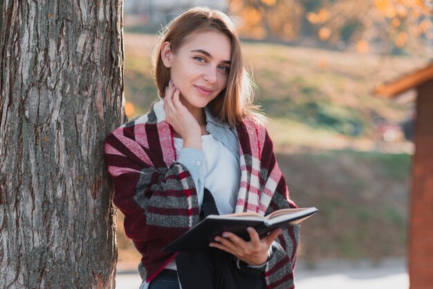 Blonde Frau, die ein Notizbuch anhält und Fotografen betrachtet