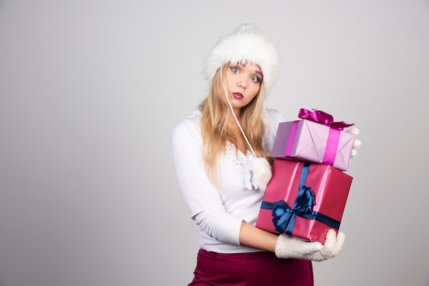 Blonde Frau, die Feiertagsgeschenke mit unruhigem Ausdruck hält.