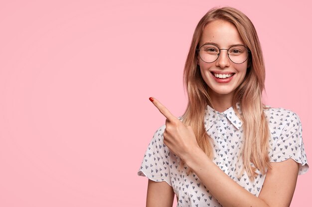 Blonde Frau, die gepunktetes Hemd und Brillen trägt