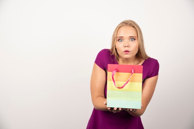 Kostenloses Foto blonde frau, die geschenktüte mit überraschtem ausdruck hält.