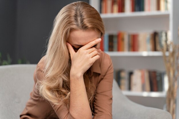 Blonde Frau, die Gesicht mit Hand bedeckt