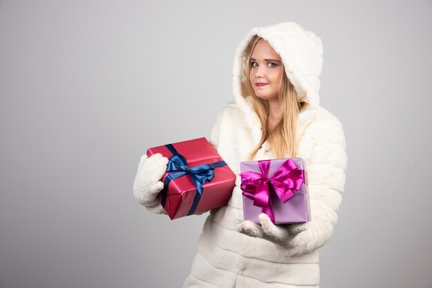 Blonde Frau, die glücklich Geschenkboxen zeigt.