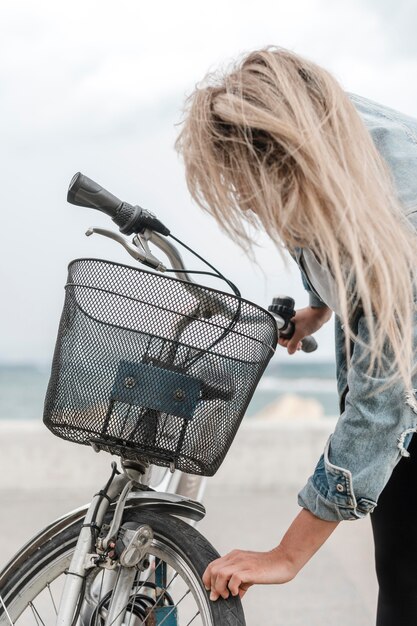 Blonde Frau, die ihr Fahrrad repariert