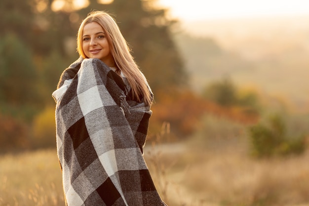 Blonde Frau, die mit einem großen Schal sich wärmt