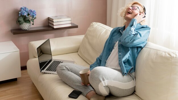 Blonde Frau, die Musik hört und Kaffeetasse hält