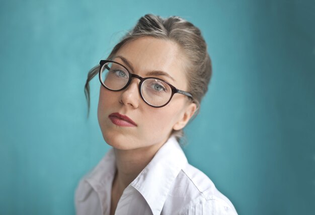 Blonde Frau, die optische Brille und ein weißes Hemd trägt