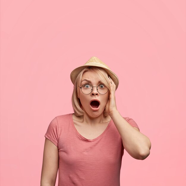 Blonde Frau, die rosa T-Shirt und Hut trägt