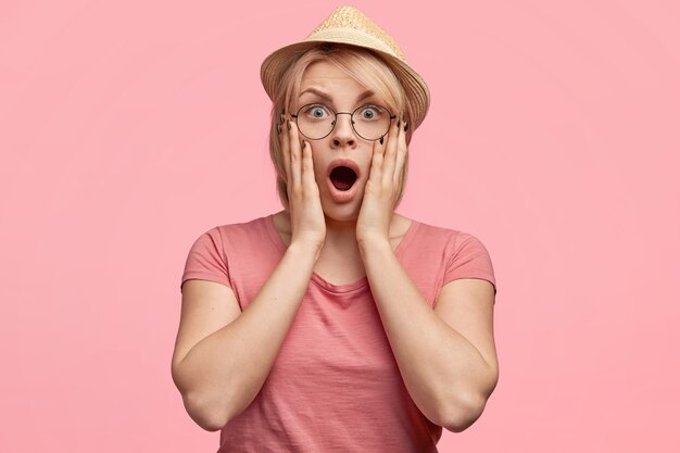 Blonde Frau, die rosa T-Shirt und Hut trägt